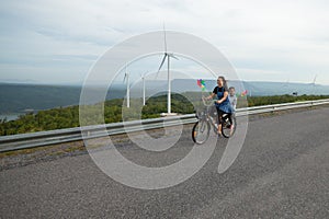 Asian child girl and mother riding bicycle and playing in the wind turbine field