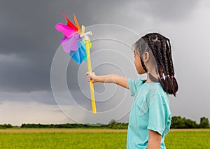 Asian child girl with pinwheels, little girl in summer day holds windmill in hand, Happy kid playing outdoors