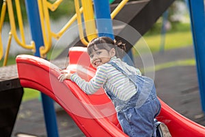 Asian Child girl playing on the outdoor playground. Kids play in school or kindergarten yard. Healthy summer activity for children