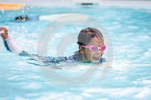 Asian child girl playing water and swimming in the swimming pool with her friend with fun.