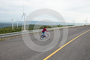 Asian child girl riding bicycle and playing in the wind turbine field