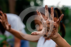 Asian child girl showing dirty hands after planting the tree