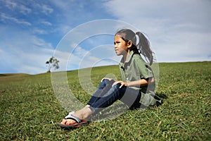Asian child girl sitting on the hill with green grass to enjoy with beautiful nature