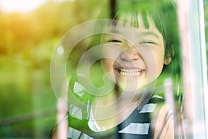 Asian child girl standing on glass mirror reflecting green forest