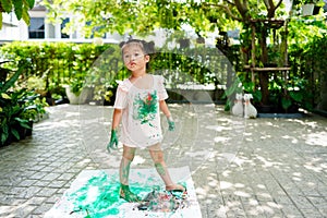 Asian child girl standing on rip canvas on tile floor on the garden background.