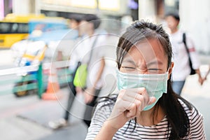 Asian child girl suffer from cough with face mask protection,sick female teen wearing medical mask because of air pollution in the