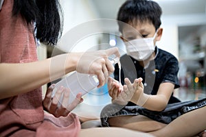 Asian child girl is using an alcohol antiseptic gel to clean her brother`s hands,Kid boy wearing a mask learning to wash hands