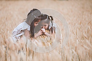 Asian child girls hugging their mother and having fun to play with mother in the barley field in vintage color tone