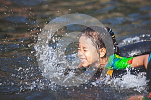 Asian  child girls playing water with inflatable ring in the river in summer time with fun and happiness