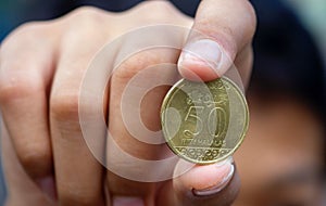 Asian child hand holding a Fifty Halalas Riyal coin, Saudi Arabia money, selected focus