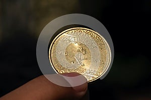 Asian child hand holding a Fifty Halalas Riyal coin, Saudi Arabia money, selected focus and dark background