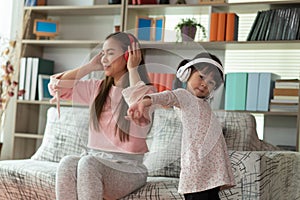 Asian child having fun and dancing with her mother in a room, active leisure and lifestyle concept