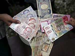 Asian child holding Indonesian rupiah, Singapore dollar, Saudi Arabia riyal, and Japan Yen money, shallow focus