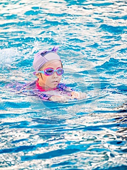 Asian child or kid girl wearing swimming suit to learning on swimming pool , learn and training swim on kick board