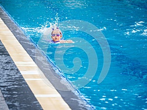 Asian child or kid girl wearing swimming suit to learning on swimming pool , learn and training swim on kick board