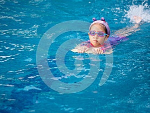 Asian child or kid girl wearing swimming suit to learning on swimming pool , learn and training swim on kick board