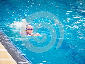 Asian child or kid girl wearing swimming suit to learning on swimming pool , learn and training swim on kick board