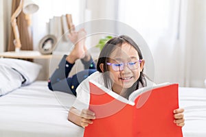 Asian child little girl reading books lying on the bed