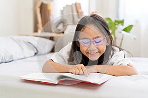 Asian child little girl reading books lying on the bed