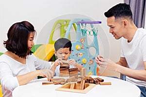 Asian child and parents playing with wooden blocks in the room at home. A kind of educational toys for preschool and kindergarten