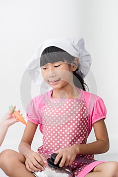 Asian child playing a chef at home.