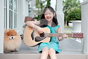 Asian Child Playing Guitar with Dog