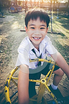 Asian child playing on manual carousel at children playground.
