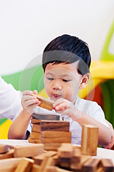 Asian child playing with wooden blocks in the room at home.