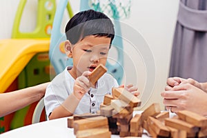 Asian child playing with wooden blocks in the room at home. A kind of educational toys for preschool and kindergarten kids