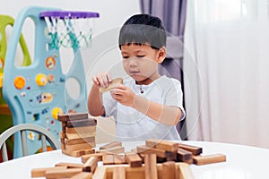 Asian child playing with wooden blocks in the room at home. A kind of educational toys for preschool and kindergarten kids