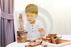 Asian child playing with wooden blocks in the room at home. A kind of educational toys for preschool and kindergarten kids.