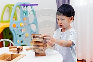 Asian child playing with wooden blocks in the room at home. A kind of educational toys for preschool and kindergarten kids.