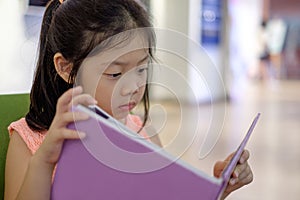 Asian Child Reading Book in Library