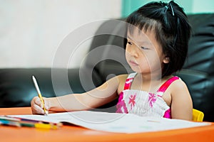 Asian child is sluggish having sleepiness while doing homework. Girl close half eyes. Cute kid aged 4-5 years old