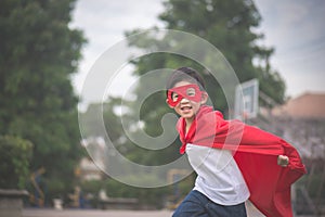 Asian child in in Superhero`s costume playing