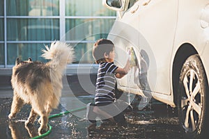 Asian child washing a car on summer day