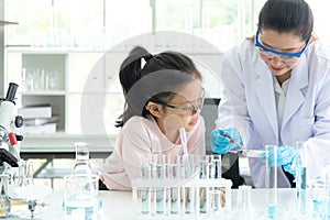 Asian children analyzing study evaluating microscope with scientist.