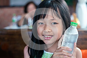 Asian children holding  and drinking cold water in restaurant. Healthy food and drink for Children concept