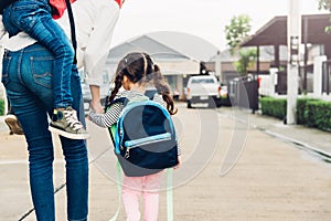 Asian children piggyback and walking with mother outdoors, the mother