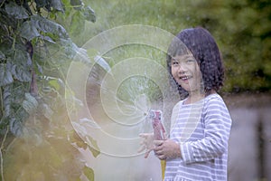 asian children playing water splashing frome a hose with happiness face in home garden