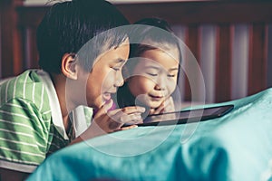 Asian children watching video and playing game on digital tablet