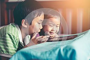 Asian children watching video and playing game on digital tablet