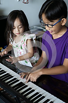 Asian children young kids playing keyboard piano at home
