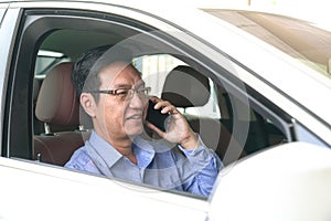 Businessman smiling and talking on his cell phone inside his car