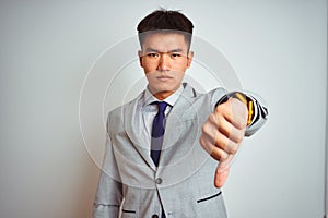 Asian chinese businessman wearing suit and tie standing over isolated yellow background looking unhappy and angry showing
