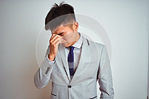 Asian chinese businessman wearing suit and tie standing over isolated yellow background tired rubbing nose and eyes feeling