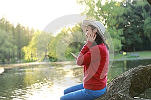 Asian Chinese careless girl is listening to music sit on a tree by a river in spring autumn park