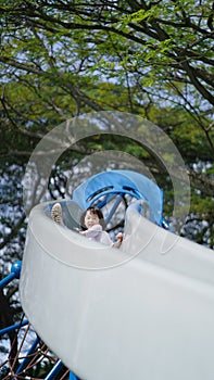 Asian chinese child coming down on slide playing sliding