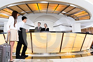 Asian Chinese couple arriving at hotel front desk photo