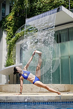 Asian Chinese female Yogi practising by the swimming pool